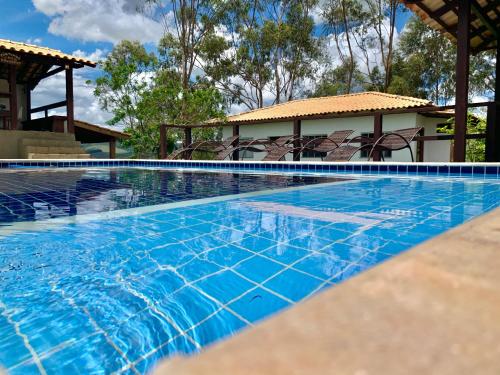 a swimming pool with blue water in front of a house at Casa de Temporada em Capitólio (Paz e Tranquilidade) in Capitólio