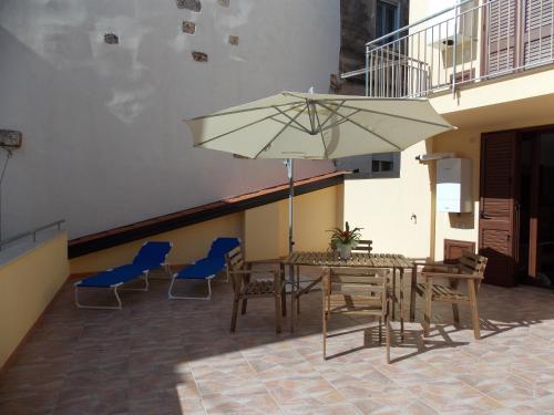 un patio con mesa, sillas y sombrilla en Residence Ideal en Alcamo