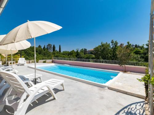 a swimming pool with two chairs and an umbrella at Holiday Home Mario by Interhome in Svetvinčenat