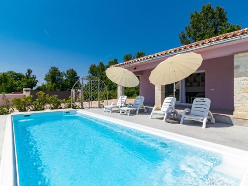 a swimming pool with chairs and umbrellas next to a house at Holiday Home Mario by Interhome in Svetvinčenat