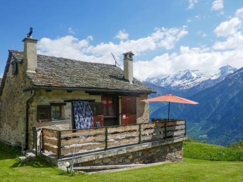 a house with an umbrella and mountains in the background at Holiday Home Rustico Tecc Berbis by Interhome in Castro