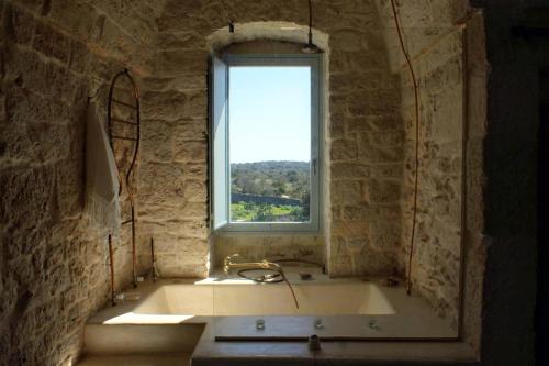 a bathroom with a bath tub with a window at Masseria LoJazzo in Ceglie Messapica