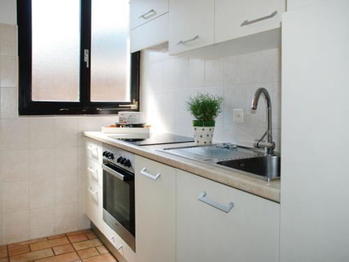 una cucina con armadi bianchi e lavandino di Apartment Casa Fiorita-2 by Interhome a Brusino Arsizio