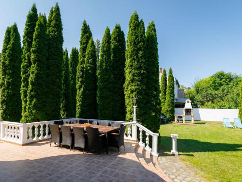 un patio con mesa, sillas y árboles en Villa Big Thuja by Interhome, en Balatonföldvár