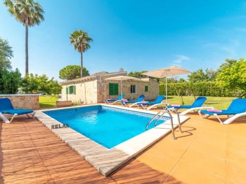 a pool with chairs and an umbrella next to a house at Villa Can Delfin by Interhome in Alcudia