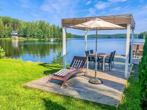 een houten terras met een tafel en een parasol bij Holiday Home Villa marina by Interhome in Padasjoki