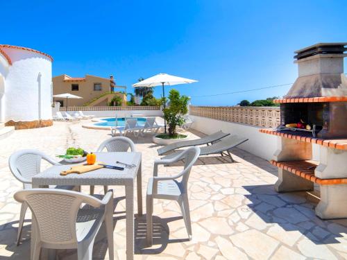 patio ze stołami i krzesłami oraz kominkiem w obiekcie Holiday Home Villa Cassandra by Interhome w mieście Calpe