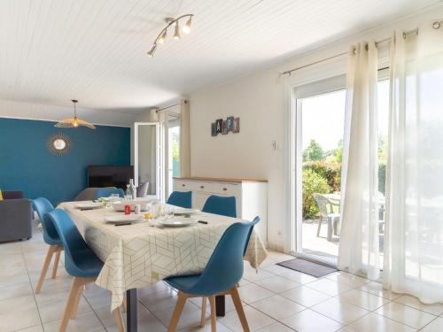 a dining room with a table and blue chairs at Holiday Home Les Trounques-1 by Interhome in Mimizan