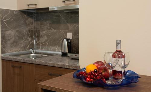 a table with a bowl of fruit and a bottle of wine at Villa Morfeas in Paralia Katerinis