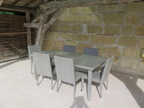 uma mesa e cadeiras num pátio com uma parede de pedra em Holiday Home Saint Martin by Interhome em Puymiclan