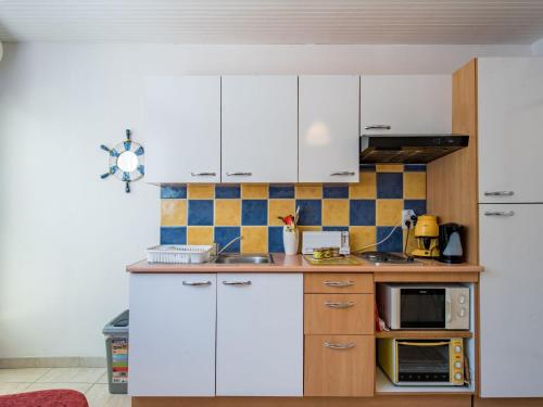eine Küche mit weißen Schränken und einer Mikrowelle in der Unterkunft Studio Le Grec by Interhome in Le Grau-du-Roi