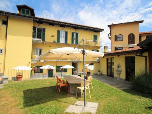 une terrasse avec une table, des chaises et des parasols dans l'établissement Apartment Giardino del Bosso-1 by Interhome, à Germignaga