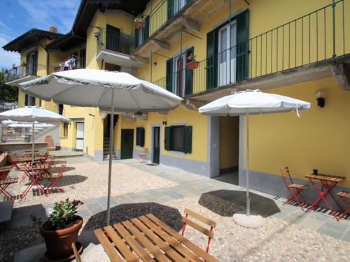 zwei weiße Regenschirme und Tische und Stühle vor einem Gebäude in der Unterkunft Apartment Giardino del Bosso-2 by Interhome in Germignaga