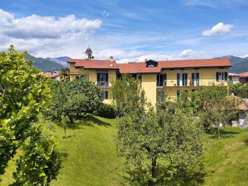ein gelbes Gebäude mit rotem Dach und einigen Bäumen in der Unterkunft Apartment Giardino del Bosso-2 by Interhome in Germignaga