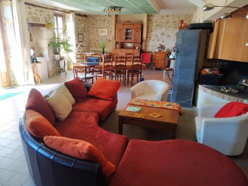 a living room with a red couch and a table at La Tribu de Lavaud in Saint-Quentin-sur-Charente