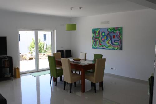 a dining room table with chairs and a painting on the wall at Casa Verde in Feteira