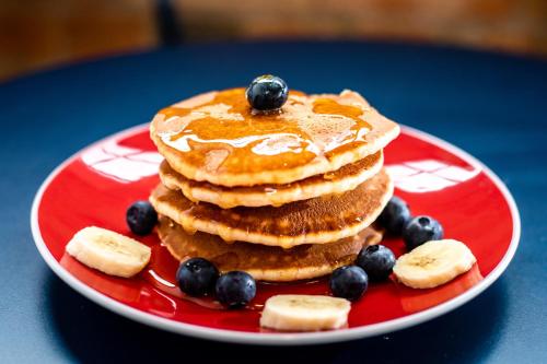 a stack of pancakes with blueberries and bananas on a red plate at Crowne Plaza Cleveland Airport, an IHG Hotel in Middleburg Heights