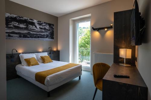 a bedroom with a bed and a desk and a window at Le Genève in La Bourboule