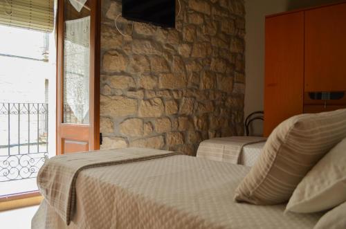 Un dormitorio con dos camas y una pared de piedra. en CAL MILIO, en Mayals