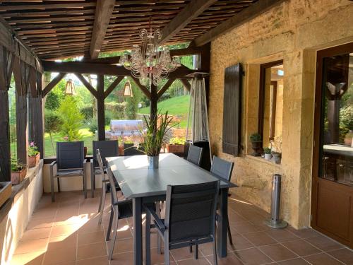 a dining room with a table and chairs on a patio at Le Noyer Résidence B&B in Le Bugue
