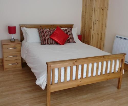 Una cama con dos almohadas rojas encima. en Quiet, cosy annexe room en Rough Close