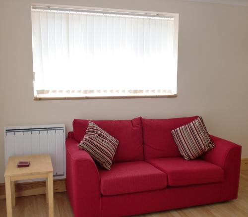 um sofá vermelho numa sala de estar com uma janela em Quiet, cosy annexe room em Rough Close