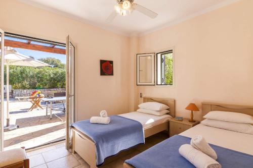 a bedroom with two beds and a balcony at Villa Dimitris Beach in Kassiopi