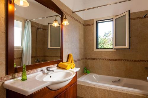 a bathroom with a sink and a tub and a mirror at Villa Dimitris Beach in Kassiopi