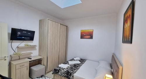 um pequeno quarto com uma cama e uma televisão em Downtown Apartment em Berat