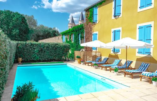 a swimming pool with chairs and umbrellas next to a building at Logis hôtel et restaurant La Bastide Cabezac in Bize-Minervois