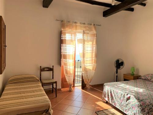 sypialnia z 2 łóżkami, krzesłem i oknem w obiekcie Casa Vittoria - panoramica in centro a Leni, Isola di Salina w mieście Leni