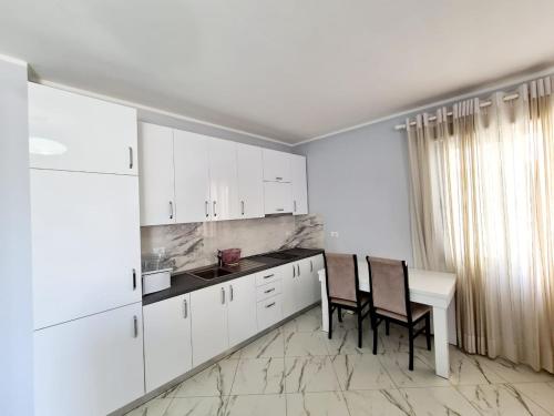 a kitchen with white cabinets and a table and chairs at Sky - Apartment - Brown in Vlorë