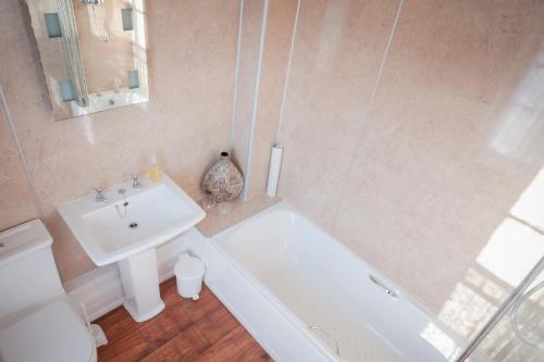 a bathroom with a sink and a toilet and a tub at The Grove Cromer in Cromer