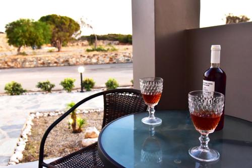 a bottle of wine and two glasses on a table at Lafo Rooms in Elafonisi