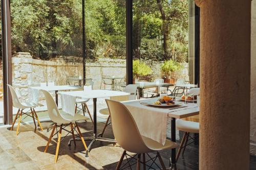 a restaurant with white tables and chairs and large windows at Villa Boscarino Boutique Hotel & Spa in Ragusa