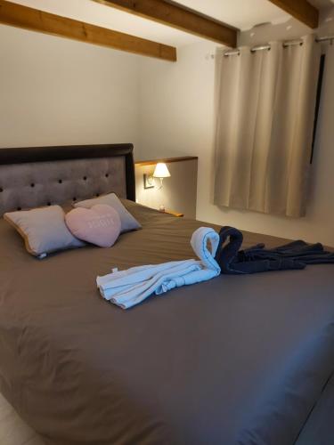 Beaumont的住宿－L'embrun de jasmin，一张带两件衬衫和毛巾的床
