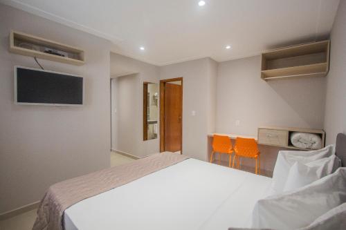 a bedroom with a bed and two orange chairs at Ilha Porchat Hotel in São Vicente