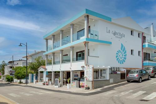 a white building with a blue trim on a street at Hotel Ristorante La Conchiglia in Cala Gonone
