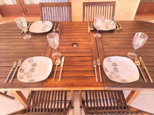 a wooden table with plates and wine glasses on it at Magnifique Villa a Tourbes proche du Cap d Agde in Tourbes