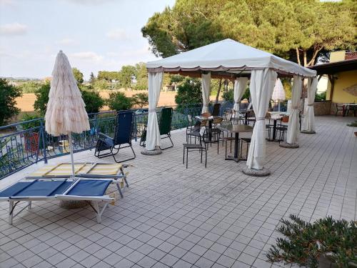 塔爾奎尼亞的住宿－Hotel Paradiso，庭院配有桌椅和白色遮阳伞。