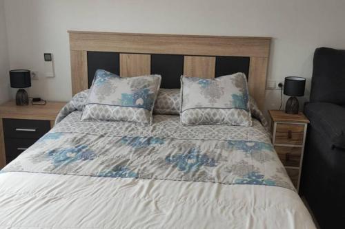 Bett mit blauer und weißer Bettwäsche und Kissen in der Unterkunft Apartamentos NayDa Studio 2 in Merida