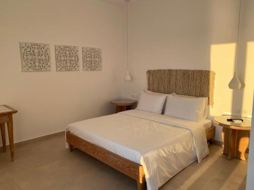 1 dormitorio con 1 cama con sábanas blancas y 2 mesas en BAY VIEW RESIDENCE en Mykonos