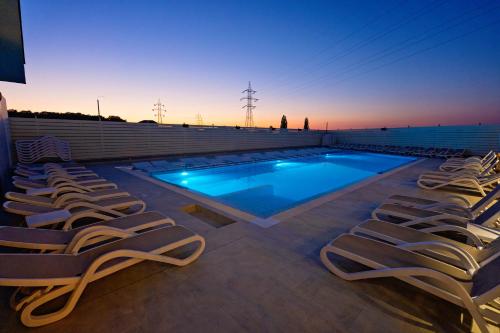 a swimming pool with lounge chairs next to a building at Hotel Aventus in Baile Felix