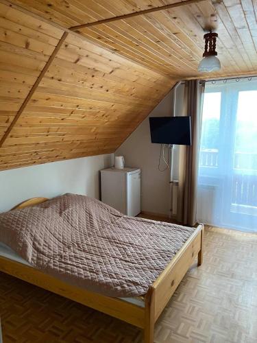 a bedroom with a bed with a wooden ceiling at Relax in Polańczyk