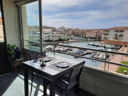 a table in a balcony with a view of a marina at CHARMANT T2 VUE MARINA PLAGES A PIED in Sète