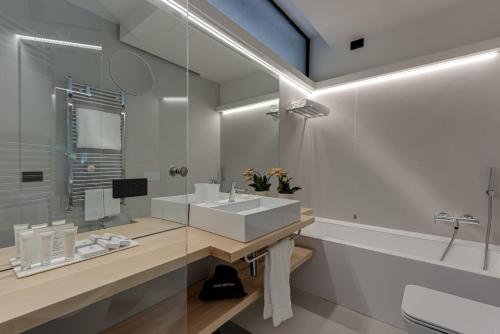 a white bathroom with a sink and a tub at Augustus Hotel & Resort in Forte dei Marmi