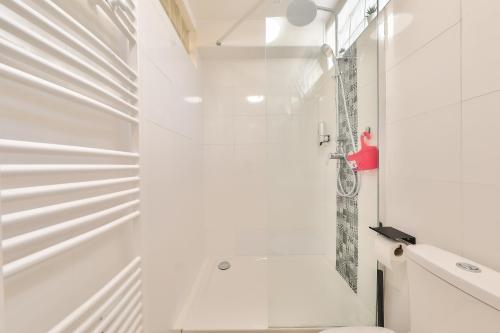 La salle de bains blanche est pourvue d'une douche et de toilettes. dans l'établissement L'Olivier - Paris Gare du Nord en 15 min -, à Deuil-la-Barre