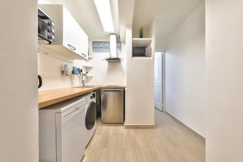 une cuisine avec des armoires blanches et des appareils en acier inoxydable dans l'établissement L'Olivier - Paris Gare du Nord en 15 min -, à Deuil-la-Barre