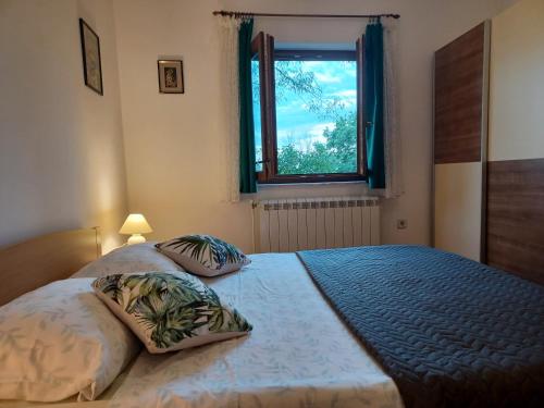 a bedroom with a bed with two pillows and a window at KAMIK 2 in Banjole