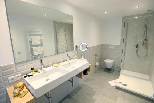a bathroom with a sink and a mirror and a toilet at Schwarzwaldhotel Oberwiesenhof in Seewald